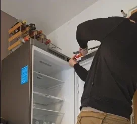 A Refrigerator technician unscrewing the front part of a fridge as repair process