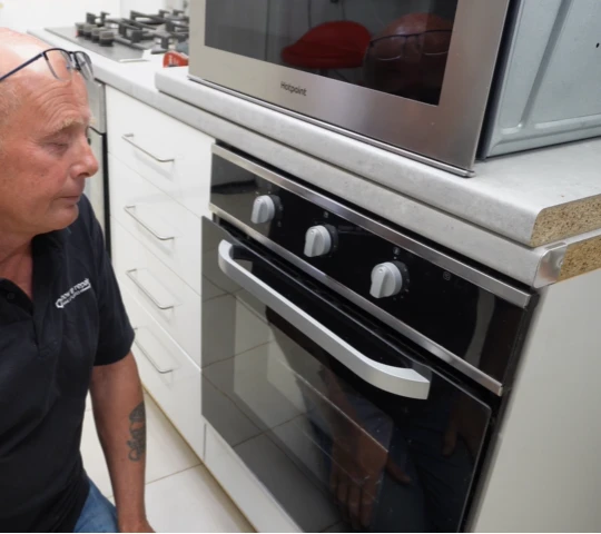 An oven repair technician inspecting a broken oven in cedar rapids